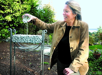 Ann Raab, who has started a consultant group in Port Townsend for green and sustainable homebuilding, demonstrates how water sifts through permeable concrete, which makes it better for the environment than regular concrete.